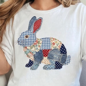 Könnte beinhalten: Weißes T-Shirt mit einem Patchwork-Hasen-Design. Der Hase besteht aus verschiedenen Stoffmustern, darunter Vichy, Blumen und Denim. Der Hase hat blaue Ohren mit roten Innenohren und sitzt.