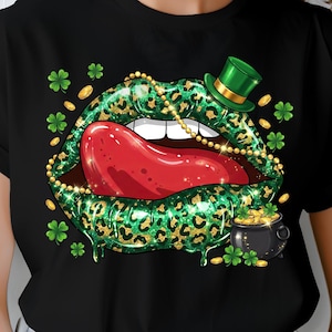 May include: Black t-shirt featuring a St. Patrick's Day design. The graphic includes green leopard print lips with a red tongue, a gold necklace, a green top hat, gold coins, shamrocks, and a pot of gold.