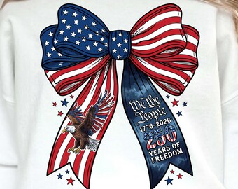Op de afbeelding: Witte sweatshirt met een patriottisch strikdesign. De strik bevat de sterren en strepen van de Amerikaanse vlag, een adelaarsafbeelding en de tekst "We the People 1776-2026 250 Years of Freedom". Rode en blauwe sterren zijn verspreid.