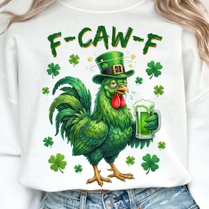 Pode incluir: Camisola branca com um galo verde de desenho animado usando um chapéu verde e segurando uma cerveja verde. O texto "F-CAW-F" está acima do galo, com trevos espalhados pelo design. O galo tem uma crista e barbela vermelhas.