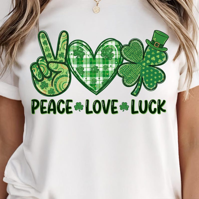 May include: White t-shirt featuring a St. Patrick's Day design. The design includes a peace sign, a heart, and a four-leaf clover, all in shades of green. The words "PEACE LOVE LUCK" are printed below the symbols.
