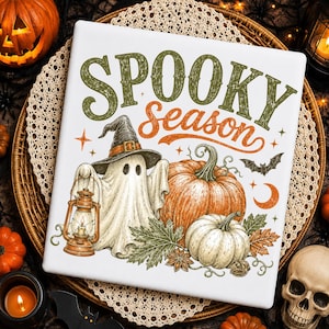 Könnte beinhalten: Ein weißes quadratisches Schild mit dem Text SPOOKY season in Grün und Orange. Die Illustration zeigt ein Gespenst mit schwarzem Hexenhut, das eine Laterne hält, zwei orangefarbene Kürbisse, grüne Blätter, eine kleine Fledermaus und eine Mondsichel.