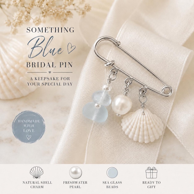 May include: A silver bridal pin with three dangling charms: sea glass beads, a freshwater pearl, and a natural shell charm. The pin is displayed on a white ribbon with the text "Something Blue Bridal Pin".