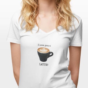 May include: White v-neck t-shirt with a graphic of a black coffee cup with latte art. The text "I love you a LATTE!" is printed above and below the coffee cup.