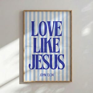 Könnte beinhalten: Ein gerahmter Druck mit einem hellen Holzrahmen. Der Druck zeigt die Worte "LOVE LIKE JESUS" in kräftigen blauen Buchstaben auf einem Hintergrund aus vertikalen blau-weißen Streifen. Der Text "JOHN 13:34" befindet sich unten.