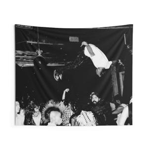 May include: Black and white tapestry featuring a concert scene. A person is mid-air, performing a flip. The crowd is visible below. The words "EXPLICIT CONTENT" are at the top. The tapestry is rectangular.