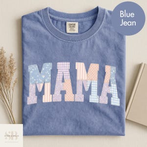 Può includere: Una maglietta blu jeans Comfort Colors con la scritta "MAMA" a lettere patchwork. Le lettere sono realizzate con vari motivi pastello, tra cui floreali, a quadri e a pois. La maglietta ha un girocollo e maniche corte.