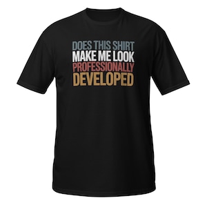 Peut inclure: Un t-shirt noir à manches courtes avec le texte "DOES THIS SHIRT MAKE ME LOOK PROFESSIONALLY DEVELOPED" imprimé en quatre lignes superposées. Les mots sont colorés en bleu sourd, blanc, rouge et beige, centrés sur la poitrine.