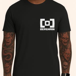 May include: Black t-shirt with a white square logo featuring a bracket design and the word "BERGHAIN" in a sans-serif font. The shirt is a classic crew neck style.