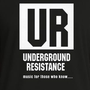 Può includere: Maglietta nera con la scritta bianca "UR" all'interno di un rettangolo bianco. Sotto, il testo bianco recita "UNDERGROUND RESISTANCE" e "music for those who know.....".