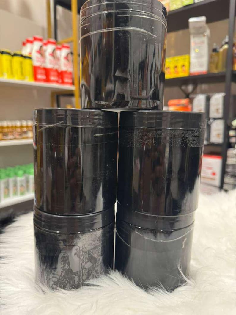 Op de afbeelding: Een stapel van zes zwarte, cilindrische containers met schroefdeksels. De containers zijn gemaakt van een glanzend materiaal en zijn gerangschikt op een witte, zachte ondergrond. Schappen met producten zijn zichtbaar op de achtergrond.
