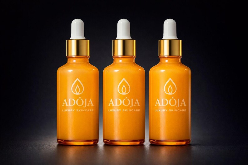 May include: Three orange glass skincare bottles with gold-colored caps and white droppers. Each bottle has the brand name "ADOJA" and "LUXURY SKINCARE" printed in white. The bottles are arranged in a row against a dark background.