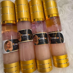 Op de afbeelding: Vier doorzichtige flessen vitamine C gezichtsserum met goudkleurige doppen en bodems. Elke fles heeft een etiket met een portret van een vrouw en de tekst "Vitamin C Face Serum". Het serum binnenin is lichtroze van kleur.