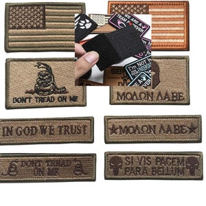 Può includere: Una collezione di toppe ricamate con temi militari e patriottici. Le toppe presentano la bandiera americana, la frase "Don't Tread on Me" e altri testi e grafiche di ispirazione militare. Le toppe sono in tonalità marroni e beige.