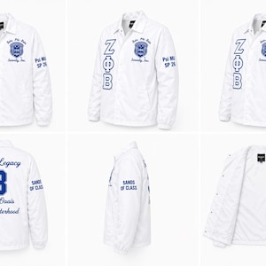 May include: White jacket with blue lettering and patches. The front features "ZΦB" and a crest, with "Psi MU SP 26" on the sleeve. The back displays "Finer Legacy 3 Team Oasis S.S. Sisterhood" and "Sands of Class".