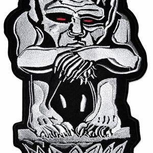 Könnte beinhalten: Gestickter Aufnäher mit einer rotäugigen Wasserspeier-Figur in Grau- und Schwarztönen. Die Figur sitzt mit verschränkten Armen, der Aufnäher hat einen schwarzen Rand. Das Design ist detailliert und im gotischen Stil gehalten.