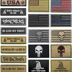Könnte beinhalten: Sammlung gestickter Aufnäher mit verschiedenen Designs und Texten. Enthält Aufnäher mit der amerikanischen Flagge, dem Satz "Don't Tread on Me" mit einer Schlange und dem Text "In God We Trust". Einige Aufnäher zeigen einen Totenkopf.