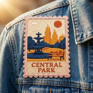 May include: A rectangular embroidered patch shaped like a postage stamp with a scalloped edge, featuring a scene of a blue fountain, a park bench with a squirrel, and yellow city buildings under an orange sun, with the text CENTRAL PARK.