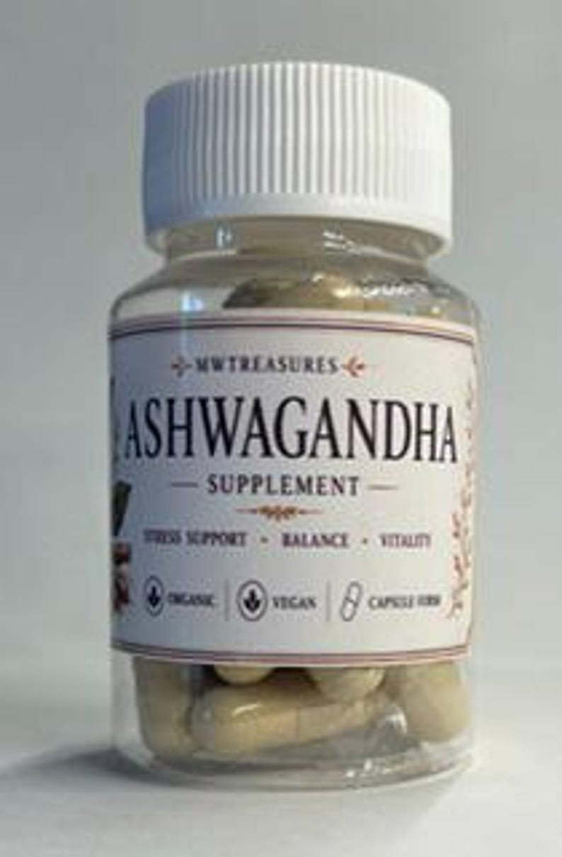 May include: A clear glass bottle with a white lid and a label that reads "Ashwagandha Supplement." The label also includes the text "Stress Support, Balance, Vitality," and "Organic, Vegan, 8 Capsule Herb."
