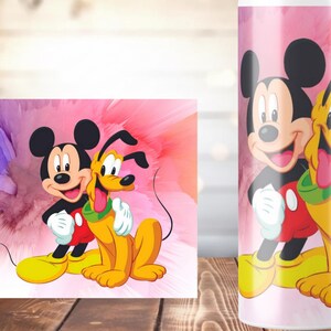 K&ouml;nnte beinhalten: Ein Becher und ein gerahmter Druck mit Micky Maus und Pluto. Die Charaktere sind in einem farbenfrohen Design vor einem rosa-violetten Hintergrund dargestellt. Der Becher hat einen rosa Hintergrund mit denselben Charakteren.