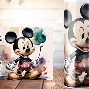 K&ouml;nnte beinhalten: Aquarellillustration von Mickey Mouse mit Luftballons. Mickey tr&auml;gt rote Shorts, gelbe Schuhe, wei&szlig;e Handschuhe und eine schwarze Jacke. Der Hintergrund zeigt farbenfrohe Aquarellspritzer. Ein passender Becher ist ebenfalls abgebildet.