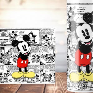 K&ouml;nnte beinhalten: Ein Becher und ein rechteckiger Gegenstand mit einem schwarz-wei&szlig;en Mickey Mouse Comic-Strip-Design. Mickey Mouse ist in seinem klassischen Outfit dargestellt: rote Shorts, gelbe Schuhe und schwarze Handschuhe. Der Becher hat einen wei&szlig;en Hintergrund.