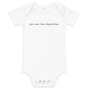 May include: White baby bodysuit with short sleeves and snap closures. The text "you are the algorithm" is printed in black, centered on the front of the garment. A simple, modern design for infants.