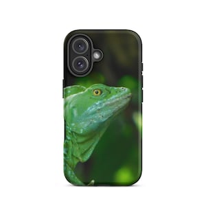 Może przedstawiać: Etui na telefon z zbliżeniem zielonej jaszczurki z żółtym okiem. Jaszczurka jest umieszczona na rozmytym zielonym tle, tworząc wzór inspirowany naturą. Etui ma czarną obwódkę i wycięcia na aparat.