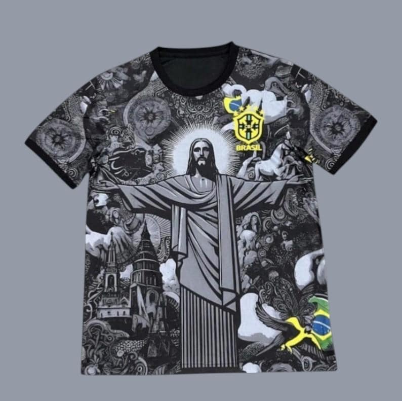 May include: Black and gray t-shirt featuring a detailed illustration of Christ the Redeemer with outstretched arms. The shirt has a black collar and sleeves, and includes the Brazilian flag and the word "Brasil".