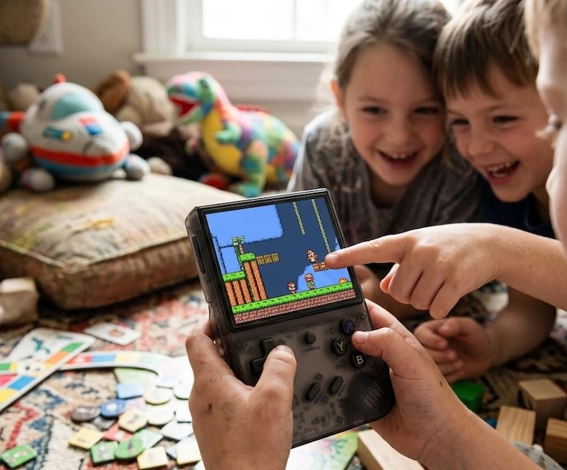 May include: A handheld video game console with a screen displaying a classic platformer game. The console is black with buttons and a directional pad. Children are smiling and pointing at the screen, surrounded by toys.