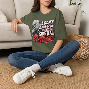 May include: An olive green short-sleeve t-shirt featuring a graphic print of a man in a suit with the text I DON'T WANT TO GO TO THE SIDE BAH Reddington in white and red lettering. The shirt has a crew neckline and a relaxed fit design.