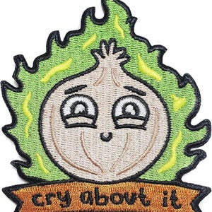 May include: Embroidered patch featuring a cartoon onion character with a smiling face, surrounded by green flames. The patch includes the text "cry about it" on a banner below the onion. The design has black, tan, green, and yellow colors.