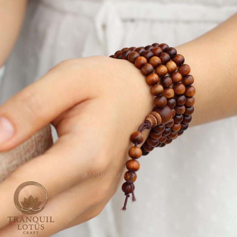 Woman wearing 108 mala beads wrapped as a multi-layer boho bracelet on wrist. Styling inspiration for wooden prayer beads as a meditation accessory and daily worry beads.