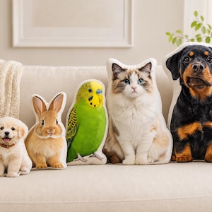May include: A collection of five shaped throw pillows featuring realistic photographic prints of animals, including a golden retriever puppy, a brown rabbit, a green parakeet, a fluffy white and brown cat, and a black and tan Rottweiler puppy.