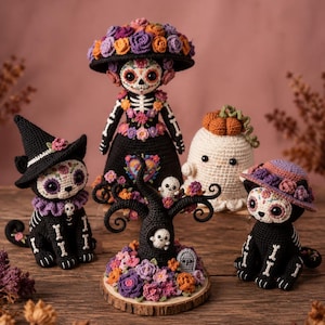 Può includere: Una collezione di cinque figure all'uncinetto che include una bambola scheletro centrale con cappello floreale, due gatti con volti decorati a teschio, un fantasma sormontato da una zucca e una scultura di albero nero con fiori su base in legno.