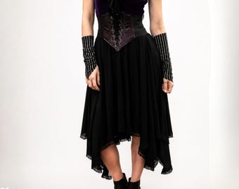 May include: A dark purple top paired with a black lace-up corset, a black high-low skirt with lace trim, and black and white pinstriped arm warmers. The ensemble features a layered skirt design with a pointed hemline and a structured waist corset.