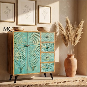 Può includere: Mobile in legno con ante e cassetti turchesi con design a foglie intagliate. L'armadio ha gambe nere e ferramenta in ottone. Un vaso in terracotta con erba della pampa essiccata è posto accanto all'armadio. Opere d'arte botaniche incorniciate sono appese al muro.