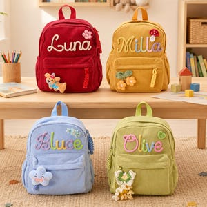 Puede incluir: Cuatro mochilas de pana en rojo, amarillo, azul claro y verde claro. Cada bolsa tiene un asa superior, un bolsillo frontal con cremallera y un nombre bordado en cursiva: Luna, Milla, Bluce u Olive. Incluyen parches decorativos de felpa.