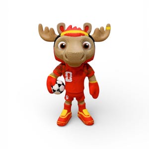 Puede incluir: Una mascota de alce de peluche con un uniforme de f&uacute;tbol rojo con el n&uacute;mero 9. La mascota tiene grandes astas marrones, una diadema negra y amarilla y sostiene un bal&oacute;n de f&uacute;tbol blanco y negro. Los zapatos son rojos y amarillos.