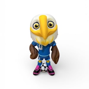 Puede incluir: Figura de un &aacute;guila con un uniforme de f&uacute;tbol azul con el n&uacute;mero 3. El &aacute;guila tiene un pico amarillo y alas marrones. Est&aacute; de pie sobre un bal&oacute;n de f&uacute;tbol y lleva zapatos rosas y negros.