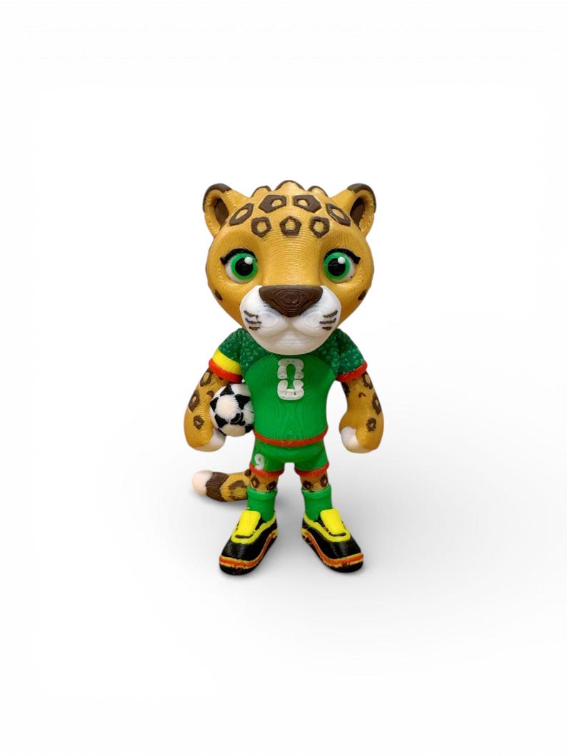 Puede incluir: Figura impresa en 3D de un guepardo de dibujos animados que lleva un uniforme de f&uacute;tbol verde con el n&uacute;mero 3. El guepardo sostiene un bal&oacute;n de f&uacute;tbol blanco y negro. El guepardo tiene un cuerpo marr&oacute;n con manchas marrones y ojos verdes.