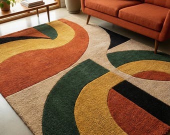 May include: A colorful area rug with an abstract design. The rug features curved shapes in shades of orange, yellow, green, black, and beige. The rug is placed on a light-colored floor, with a sofa and plants in the background.