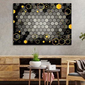 May include: Abstract geometric wall art featuring a honeycomb pattern in shades of gray and black, accented with yellow hexagonal shapes. The artwork is displayed above a wooden cabinet with decorative items.