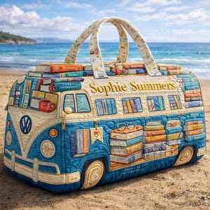 May include: A quilted tote bag in the shape of a blue and white Volkswagen bus, decorated with stacks of books and the name "Sophie Summers" embroidered in gold. The bag has a handle with a book-themed pattern and is on a sandy beach.