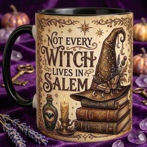 May include: A ceramic mug with a black handle and rim, featuring a beige background with the text "Not every witch lives in Salem." The design includes a pointed hat on a stack of three books, a lit candle, and a bottle with a bat illustration.