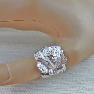 May include: A silver ring featuring a detailed rose design. The rose is three-dimensional and has a textured surface.