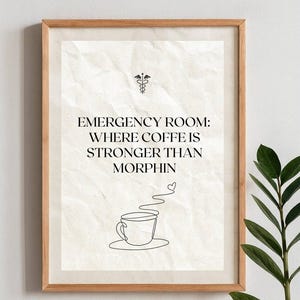 Könnte beinhalten: Gerahmter Druck mit hellbeigem Hintergrund und Holzrahmen. Der Text lautet „NOTAUFNAHME: WO KAFFEE STÄRKER IST ALS MORPHIN“ mit einer Strichzeichnung einer Kaffeetasse und einem medizinischen Symbol.