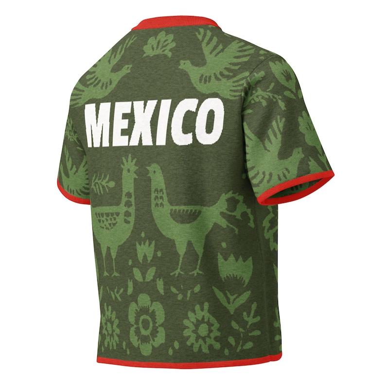May include: Olive green t-shirt with red trim and the word "MEXICO" in white block letters. The shirt features a repeating pattern of green birds, flowers, and other decorative elements.