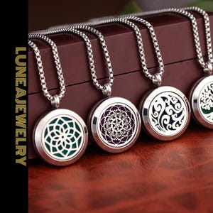 Könnte beinhalten: Vier silberfarbene Anhänger-Halsketten mit aufwendigen Designs. Jeder runde Anhänger hat ein anderes Muster: ein Blumendesign, ein Mandala, wirbelnde Formen und ein Lebensbaum. Die Anhänger hängen an einer silbernen Kette.