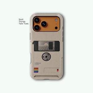 May include: A beige phone case featuring a retro floppy disk design with a mustard yellow camera area. The case displays the text Good Things Take Time, Classic 84, 1.44 MB, a grid landscape graphic, and a small rainbow square icon.